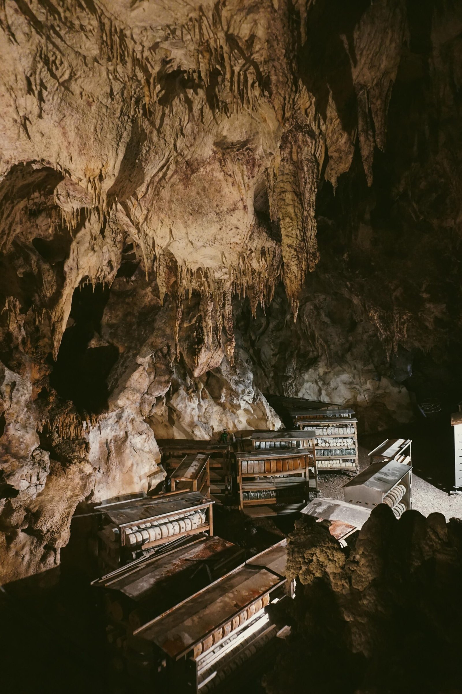 Estanterías de madera con quesos Gamonéu en el interior de una cueva con estalactitas